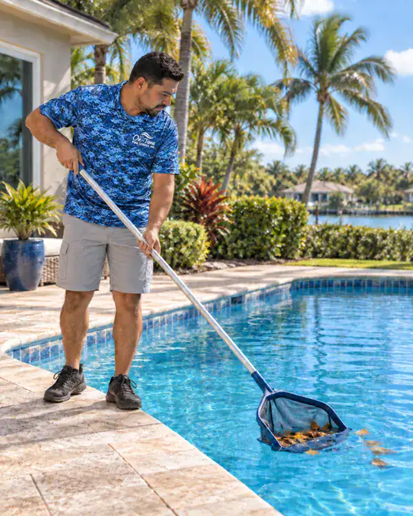Pool technician skimming leaves during weekly pool service in Sarasota, Florida